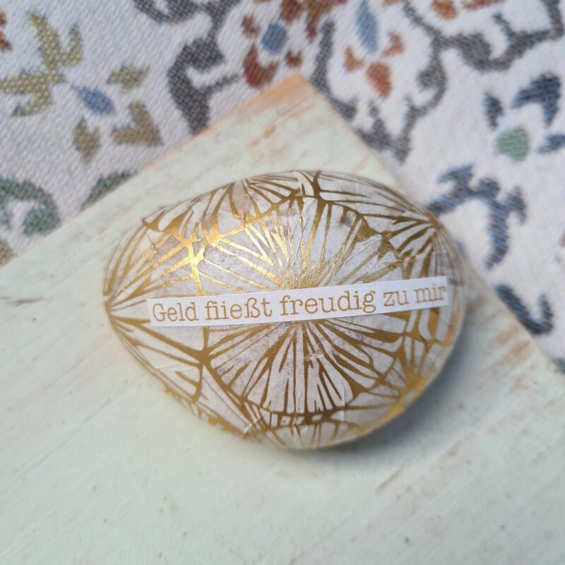 Stein mit dem Text Geld fließt freudig zu mir