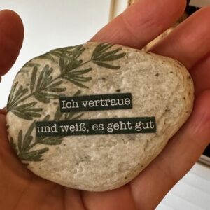 Stein in der Hand mit Aufschrift Vertraue
