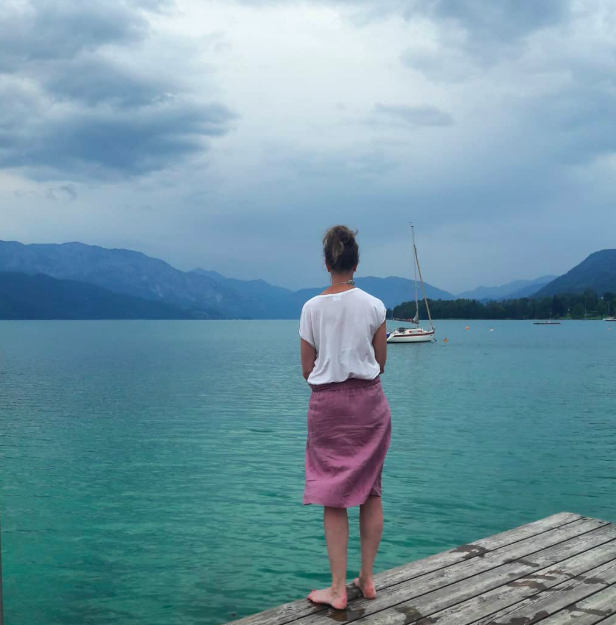 frau mit rosa rock steht am wasser
